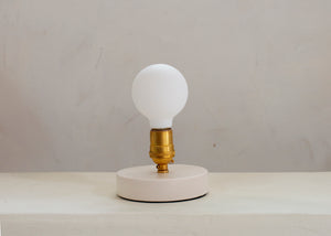 a clean and elegant addition to a nightstand or reading nook, the Simple Lamp is just that — simple. A hand cast porcelain base anchors a brass socket with a natural living finish that will patina over time. Fitted with a touch sensor, you turn the Simple Lamp on or off by simply taping the brass socket with a finger. 