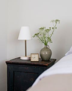 Our surface lamp is the perfect small lamp for your counter, dresser, desk, or bedside table. Brass and porcelain with linen shade, classic, simple, clean design, old house style, cottage, English, hudson valley, bedside table, bedroom design, antiques