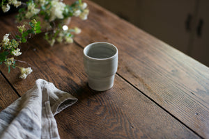 An elegant cup for every beverage at every temperature. This form is inspired by ceramics found in archaeological digs at the Historic 1747 Parsonage in Germantown, New York. Coffee cup, wine cup, porcelain, linen, old house style, old table, smoke, grey, gray