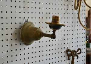 This is an antique brass sconce with a candle cup detail below the socket. Quittner. 