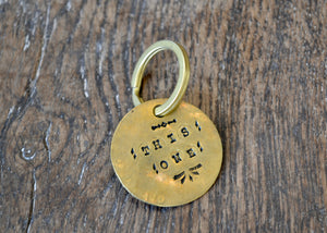 A solid brass key tag hand stamped in our workshop with “This One". Each piece is one-of-a-kind and comes on a brass key ring.