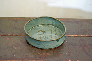 a green metal bowl sitting on top of a street 