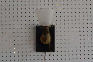 This is an antique brass sconce mounted on a wood backplate that is to be hung on the wall off of a screw or nail. It is operated with a pull-chain, and has a 6 foot long cloth-covered cord.