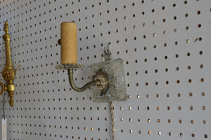 a vintage glass plug-in sconce that is to be hung on the wall off of a screw, nail, or hook. It is operated with a switch on the socket, and has a 6 foot long cloth-covered cord. It was previously damaged, and a former owner added the metal bracket for hanging.