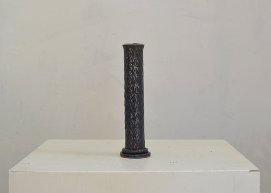 A bud vase for your breakfast table or bedside. Made by hand for single blooms or small sprays. It features a pressed zigzag motif and a blue glaze.