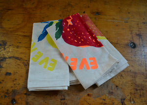 Two fabric napkins with colorful designs and on a wooden surface