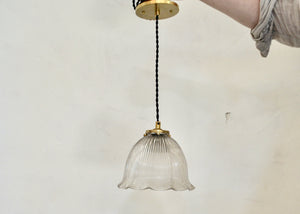 Antique glass Holophane pendant with a bell-shaped form. Cast brass shade holder and brass hardware. Cloth-covered cord. Ideal for over a kitchen or pantry sink, or in a laundry or powder room. Quittner.