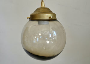 Vintage-style pendant light with glass shade and brass fitting on a plain background
