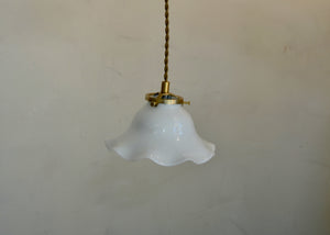 Antique glass pendant with a scalloped form. Cast brass shade holder and brass hardware. Cloth-covered cord. Ideal for over a kitchen or pantry sink, or in a laundry or powder room. Quittner.
