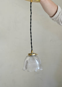 Antique glass Holophane pendant with a bell-shaped form. Cast brass shade holder and brass hardware. Cloth-covered cord. Ideal for over a kitchen or pantry sink, or in a laundry or powder room. Quittner.