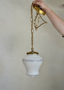 White pendant light with gold chain against a plain background