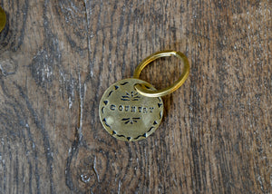 Brass keychain with engraved text on a wooden surface