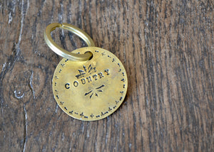 brass key tag with "Country" hand stamped on it. 