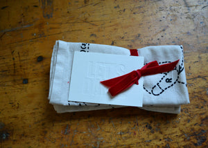 Stack of natural cotton napkins with a red ribbon on a wooden surface