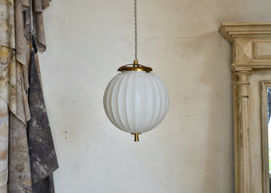 Art Deco-era vintage pendant light featuring a ribbed frosted glass orb and brass details, offering a warm glow. Rewired. Quittner.