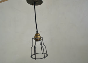 Vintage-style pendant light with metal cage and brass fitting against a plain background