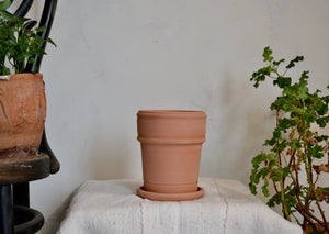 Small planter pot hand-thrown in terra cotta with ribbed detail and built-in drainage tray. This pot is ideal for use as for herbs in your kitchen, a seasonal flower like a pansy or marigold, or a single bulb. Firehouse Pottery Co. Quittner
