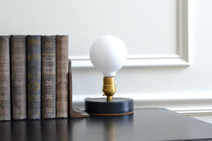 Designed to be a clean and elegant addition to a nightstand or reading nook, the Simple Lamp is just that — simple. A hand cast porcelain base anchors a brass socket with a natural living finish that will patina over time. Fitted with a touch sensor, you turn the Simple Lamp on or off by simply taping the brass socket with a finger. Quittner