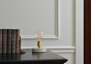 Designed to be a clean and elegant addition to a nightstand or reading nook, the Simple Lamp is just that — simple. A hand cast porcelain base anchors a brass socket with a natural living finish that will patina over time. Fitted with a touch sensor, you turn the Simple Lamp on or off by simply taping the brass socket with a finger. Quittner.