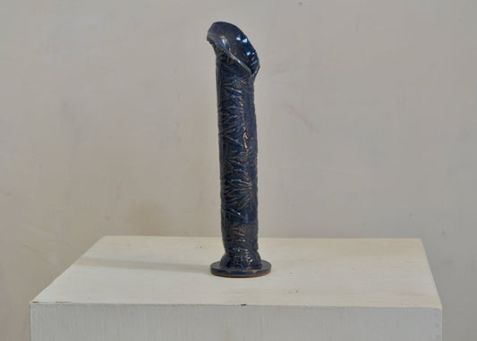 A bud vase for your breakfast table or entryway. Made by hand for single blooms or small sprays. It features a pressed coneflower motif and a blue glaze. Quittner.