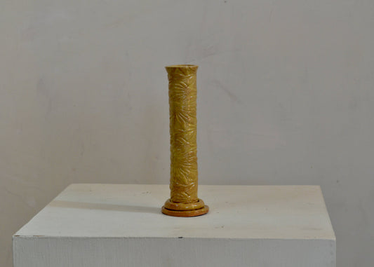A bud vase for your breakfast table or bedside. Made by hand for single blooms or small sprays. It features a pressed coneflower motif and a yellow glaze. Quittner. Lara Gillett.